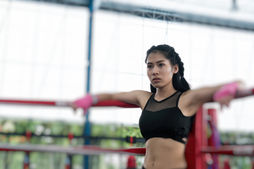 A determined woman training in a boxing ring with golden sunset light hitting the canvas, representing the fierce warrior energy of the Aries Sun and Mars in Leo trine.