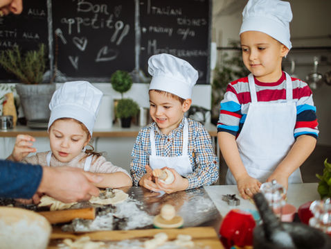 Three children with a man, baking cookies in the kitchen,