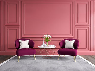 Two purple armchairs with white cushions face each other in a pink-walled room