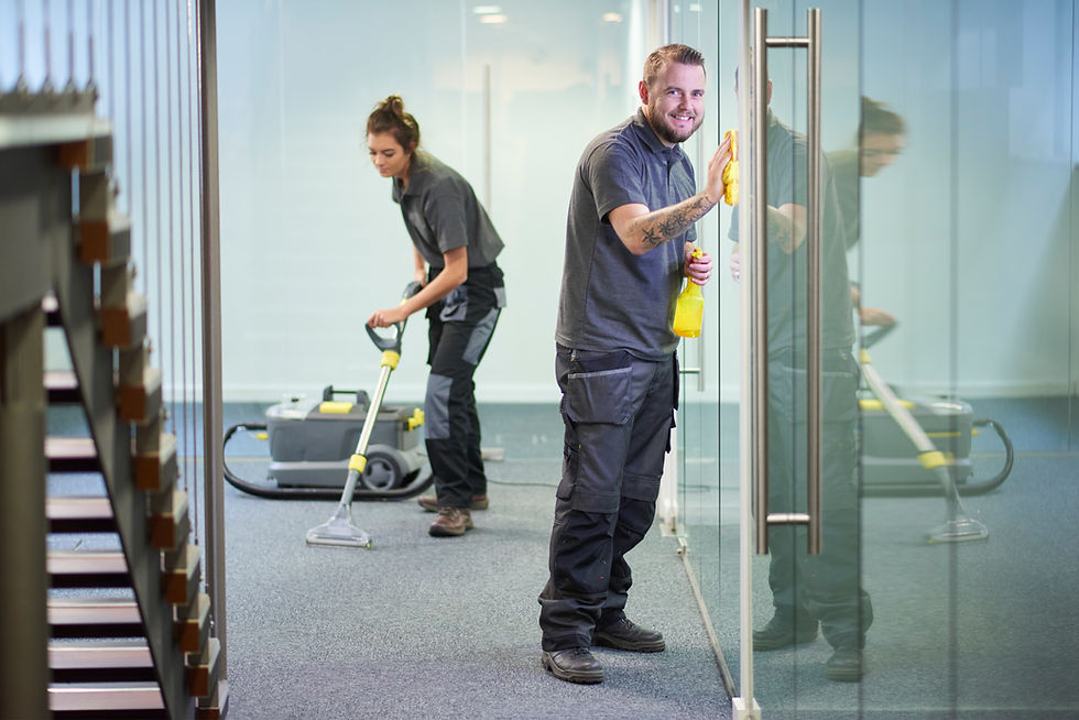 Two cleaners working in an office, vacuuming floors and cleaning glass