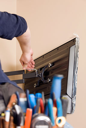 A worker is using a hex wrench to install a new TV to a wall