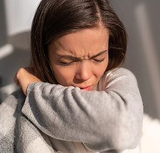 Image of woman sneezing facing the sun