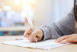 Hand holding pencil writing on looseleaf paper