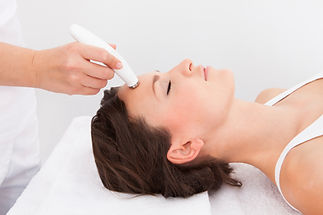 Close up of a woman receiving a gentle skin tightening treatment on her forehead