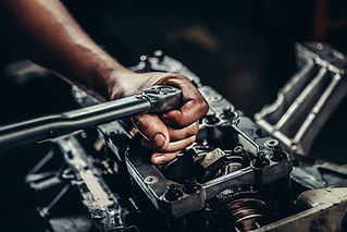 Close-up of a man's hand using a ratchet on an engine part