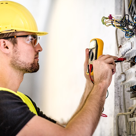 Electrician repairing circuit breakers in industrial electric panel