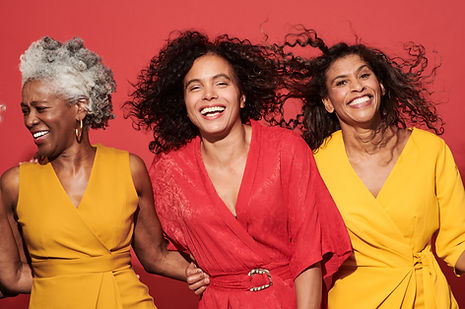 Three African American women smiling with a red background