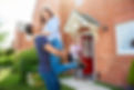a couple embrace in front of their new home , in the background an estate agent looks on