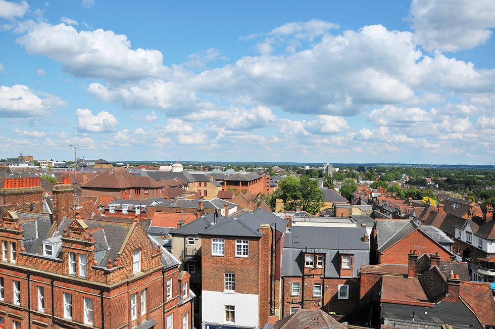 Elevated rooftop view of red brick buildings and tiled roofs in St. Albans under a partly cloudy sky