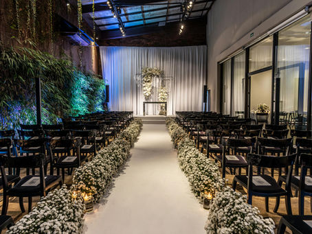 a wedding aisle with black chairs and white flowers