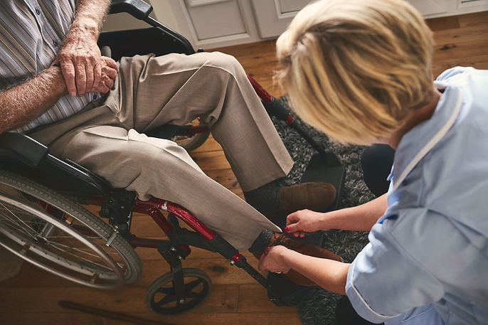 Friendly carer assisting an elderly person in a wheelchair with their footwear