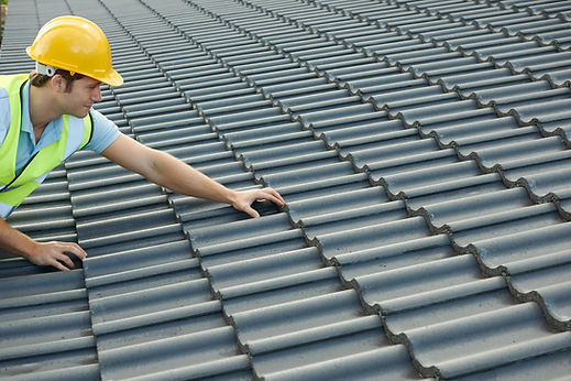 Professional roofer inspecting slate roof tiles on a house roof