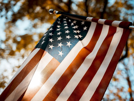 The American flag waves proudly against a backdrop of golden foliage, capturing the essence of autumn and national pride.