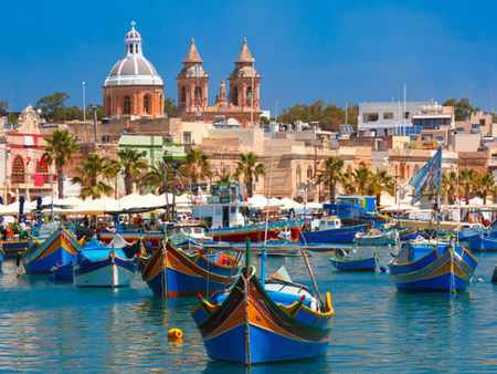 Colourful traditional fishing boats, known as "luzzu," gently float in the azure waters of Marsaxlokk, Malta.