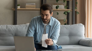 Pessoa sentada em frente a um notebook analisando uma planilha de gastos, simbolizando organização financeira e construção de prosperidade.