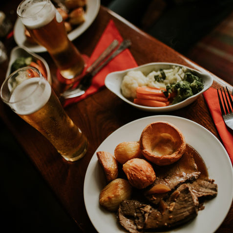 Traditional roast dinner with vegetables and two beers
