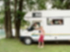 A Man and His Young Children Sit Inside a Motor Home Parked by a Lake