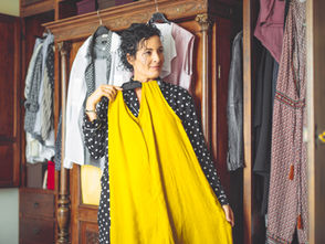 A woman holding up a yellow dress