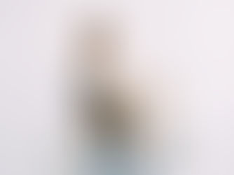 Woman standing in a bright, minimal room holding and looking at a gift box she has just received.