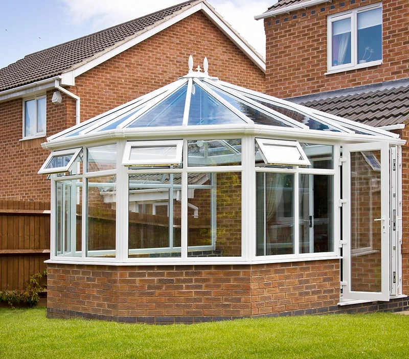 a classic multi-faceted bay-fronted conservatory, likely a Victorian-style design, with a white uPVC frame
