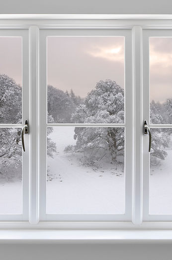 A snowy landscape viewed through a white-framed window