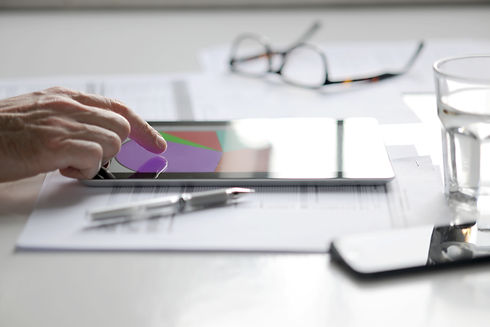 Eyeglasses, tablet displaying charts, and pen on a desk representing financial options