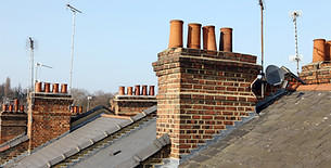 Professional builder carrying out repointing and repairs on house chimney stack