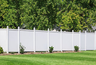 White vinyl fence running across a homeowners back yard