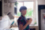 A woman in a kitchen holding a mug of tea close to her chest