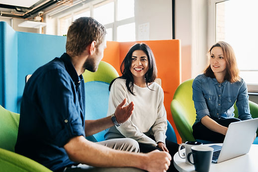 Colleagues talking happily while seated in colourful office chairs