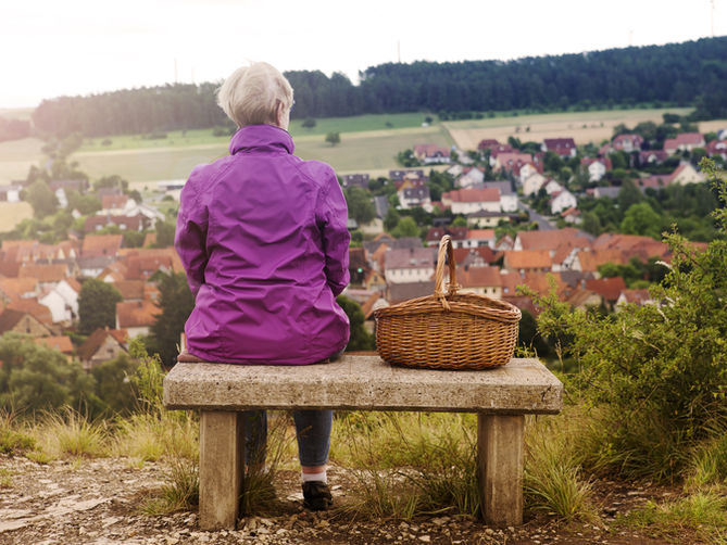 Woman overlooking town with a basket next to her.