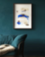 Framed abstract art with blue and beige brushstrokes on a teal wall. A teal sofa with a faux fur throw creates a cozy, artistic vibe.