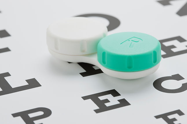 Green and white contact lens case resting on an eye chart