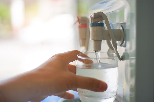 Male hand serving water of a water cooler in plastic cup