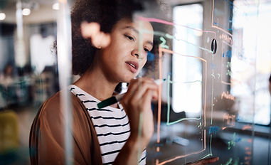 woman looking at a transparent white board with a dry erase marker in her hand.