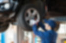 A mechanic works on a car tyre with a power tool in a garage