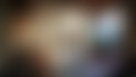 Four-poster bed with white curtains in a sunlit room. Brick walls, terracotta floor, large window view of green hills. Cozy and serene.