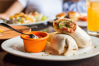 A close-up view of burritos with salsa sauce on a dining table