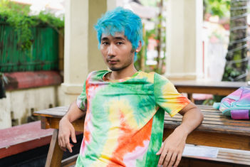 Person with blue hair and colorful tie-dye shirt