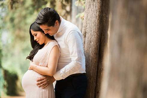 Man embracing his pregnant wife as they admire her pregnant belly