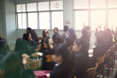 Alunos levantando as mãos na sala de aula