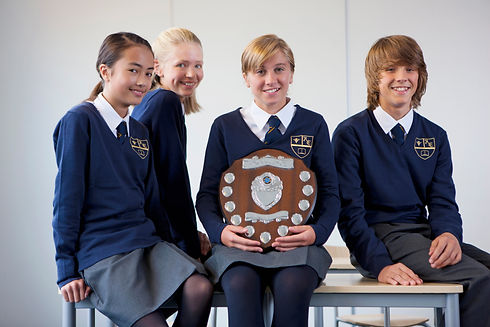 Portrait of smiling students in school uniforms holding award plaque