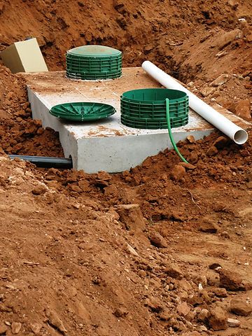 A concrete base with green septic tank components and pipes