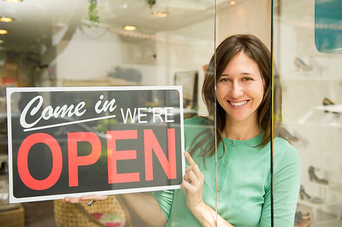 woman holding open sign in shoe store