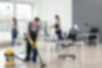 A man and woman vacuuming an office, focused on cleaning the carpet and maintaining a tidy workspace