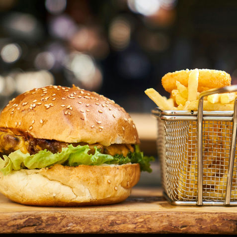 Hamburger, fries, and onion rings on a wooden board