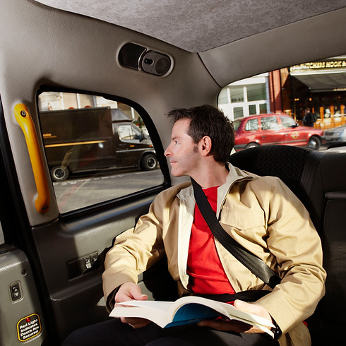 A man in a taxi wears a seatbelt and beige jacket