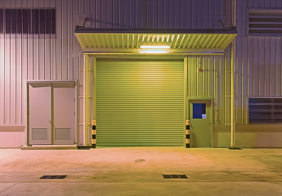 A dimly lit, industrial loading dock with a closed green roller door