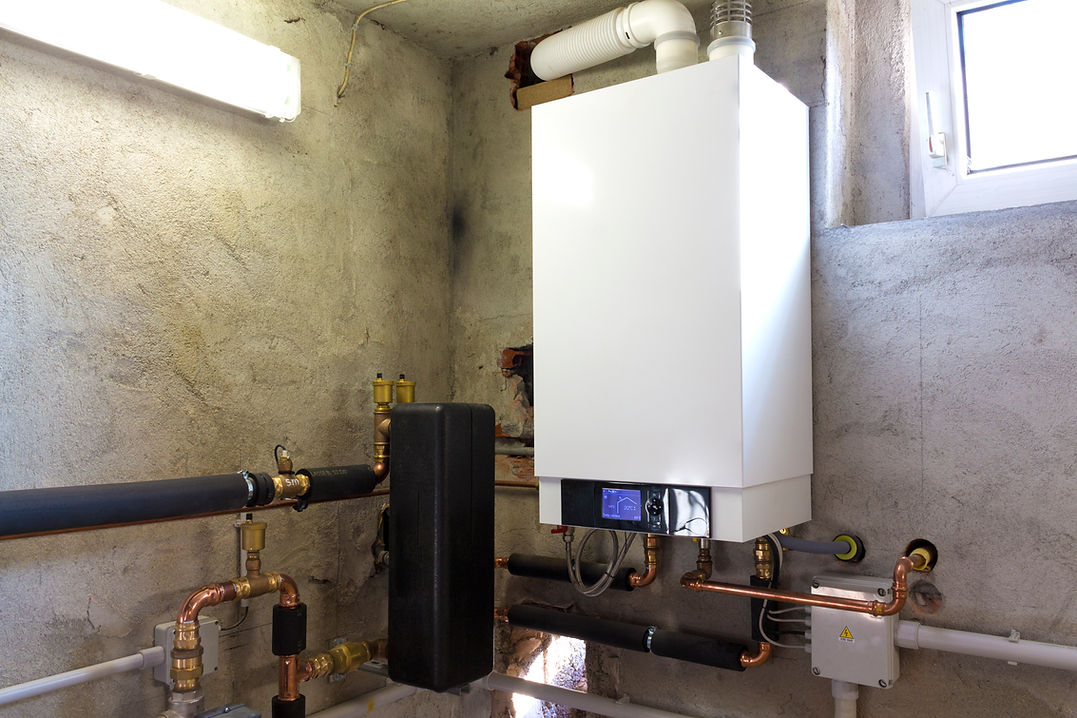 A white boiler unit mounted on a concrete wall