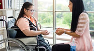 A woman and another woman on a wheelchair